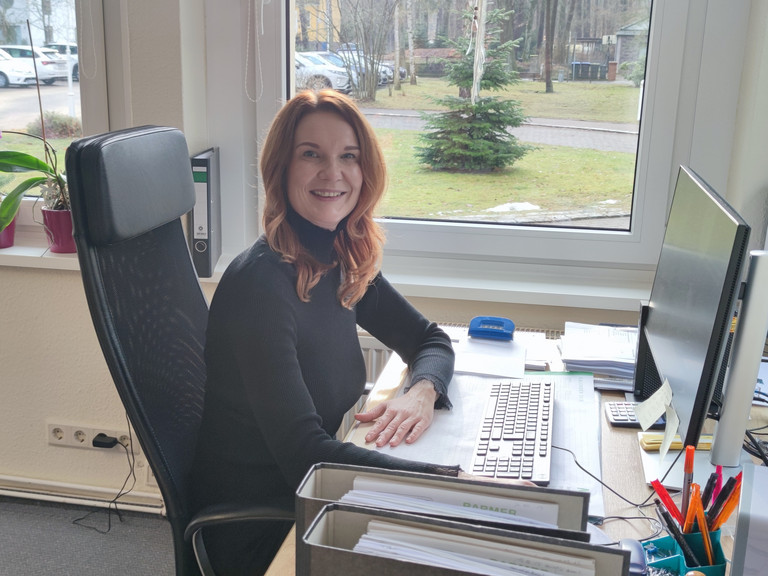 Umschülerin Christina blickt während ihres Praktikums im Immanuel Haus Ecktannen am Schreibtisch mit Monitor sitzend lächelnd in die Kamera Umschülerin Christina blickt während ihres Praktikums im Immanuel Haus Ecktannen am Schreibtisch mit Monitor sitzend lächelnd in die Kamera